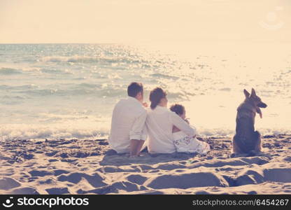 happy young family in white clothing have fun and play with beautiful dog at vacations on beautiful beach