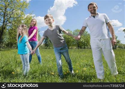 Happy young family of couple and two children spending time in summer park. Happy family in park