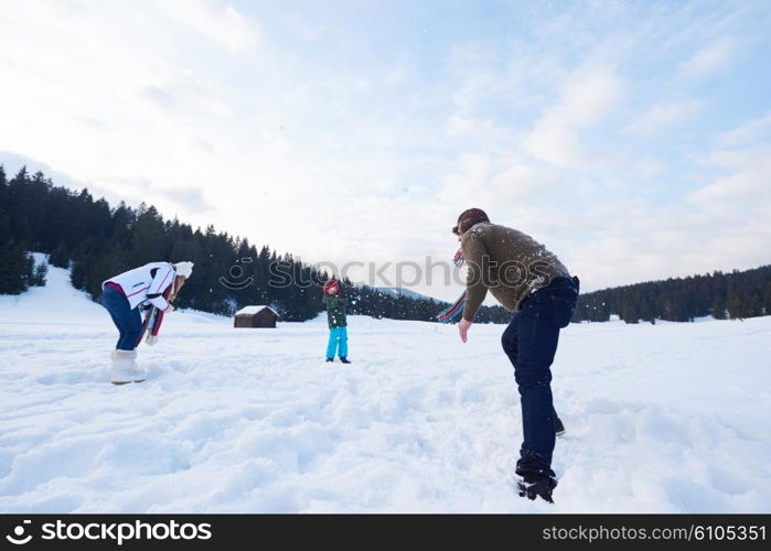 happy young family playing in fresh snow at beautiful sunny winter day outdoor in nature