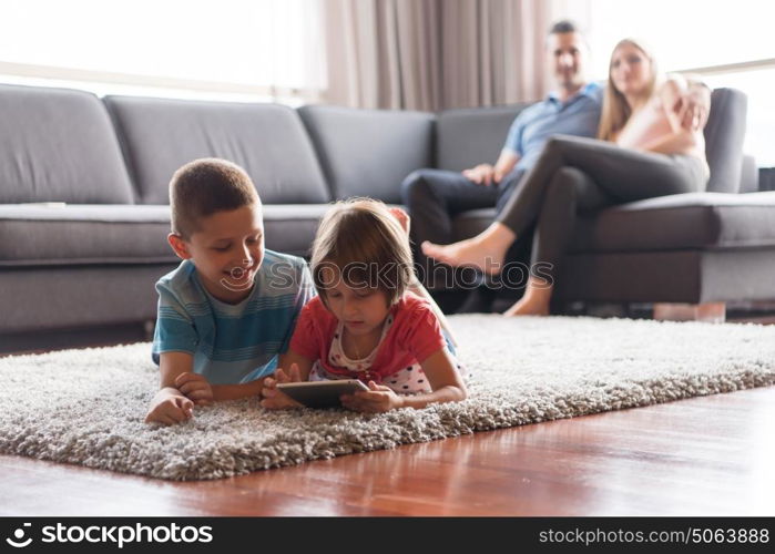 Happy Young Family Playing Together at home.kids using tablet on the floor