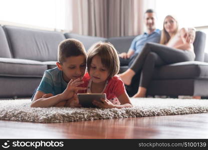 Happy Young Family Playing Together at home.kids using tablet on the floor