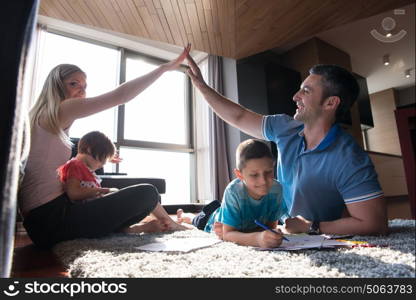 Happy Young Family Playing Together at home on the floor using a tablet and a children&rsquo;s drawing set