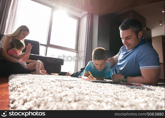 Happy Young Family Playing Together at home on the floor using a tablet and a children&rsquo;s drawing set