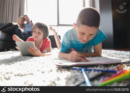 Happy Young Family Playing Together at home on the floor using a tablet and a children&rsquo;s drawing set