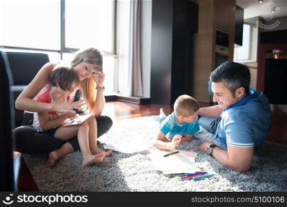 Happy Young Family Playing Together at home on the floor using a tablet and a children&rsquo;s drawing set