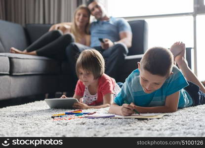 Happy Young Family Playing Together at home on the floor using a tablet and a children&rsquo;s drawing set