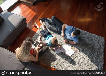 Happy Young Family Playing Together at home on the floor using a tablet and a children&rsquo;s drawing set top view