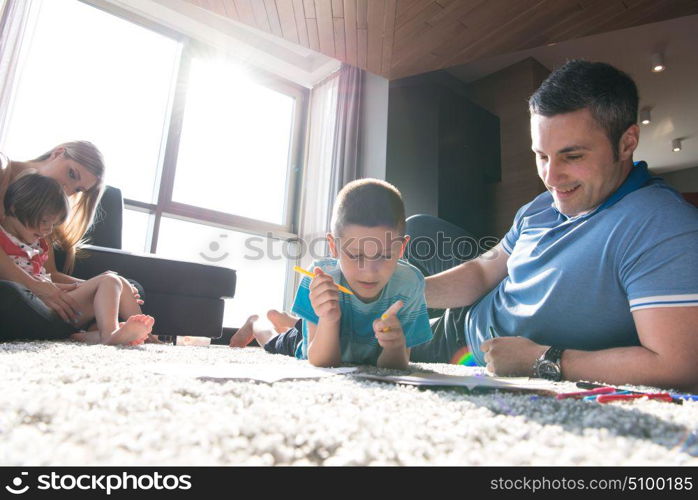 Happy Young Family Playing Together at home on the floor using a tablet and a children&rsquo;s drawing set