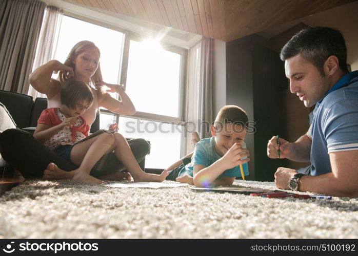 Happy Young Family Playing Together at home on the floor using a tablet and a children&rsquo;s drawing set