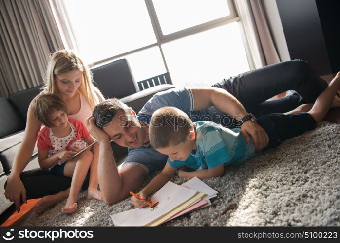 Happy Young Family Playing Together at home on the floor using a tablet and a children&rsquo;s drawing set