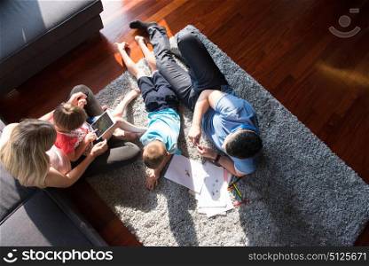 Happy Young Family Playing Together at home on the floor using a tablet and a children&rsquo;s drawing set top view