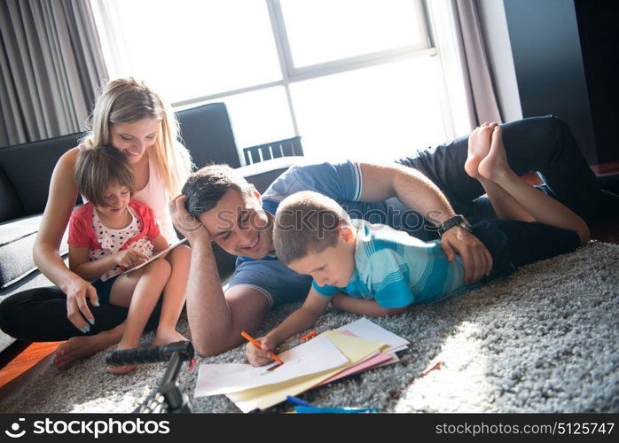 Happy Young Family Playing Together at home on the floor using a tablet and a children&rsquo;s drawing set