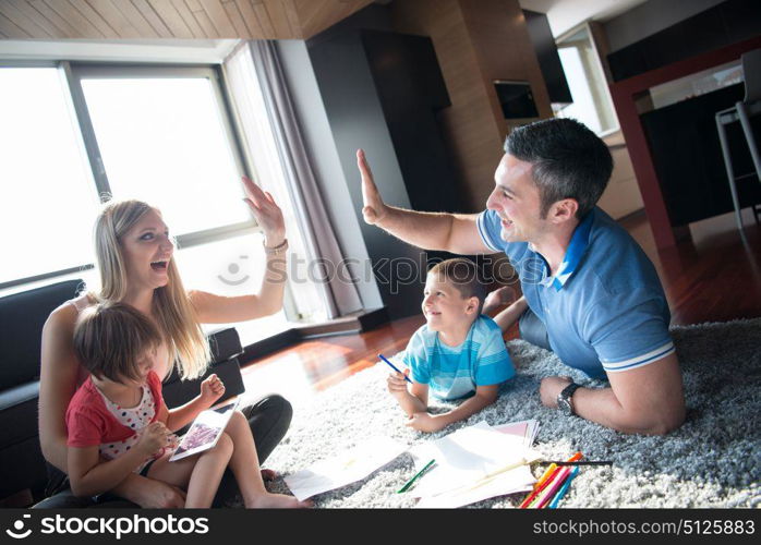 Happy Young Family Playing Together at home on the floor using a tablet and a children&rsquo;s drawing set