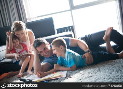 Happy Young Family Playing Together at home on the floor using a tablet and a children&rsquo;s drawing set