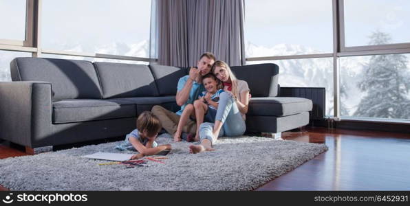 Happy Young Family Playing Together at home on the floor using a tablet and a children&rsquo;s drawing set