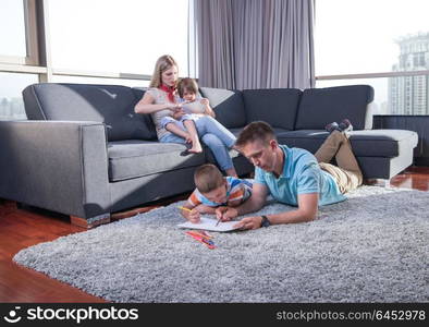 Happy Young Family Playing Together at home on the floor using a tablet and a children&rsquo;s drawing set