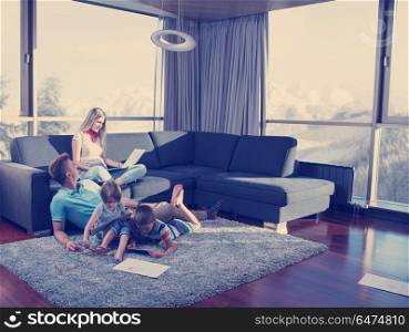 Happy Young Family Playing Together at home on the floor using a laptop computer and a children&rsquo;s drawing set. young couple spending time with kids at home