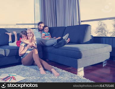 Happy Young Family Playing Together at home on the floor using a tablet and a children&rsquo;s drawing set. young couple spending time with kids