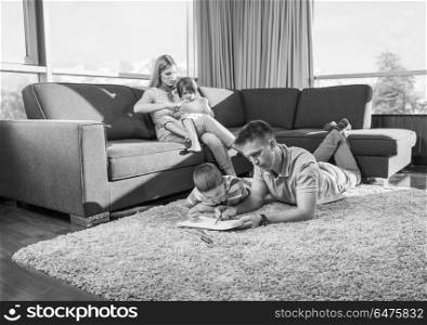 Happy Young Family Playing Together at home on the floor using a tablet and a children&rsquo;s drawing set. young couple spending time with kids