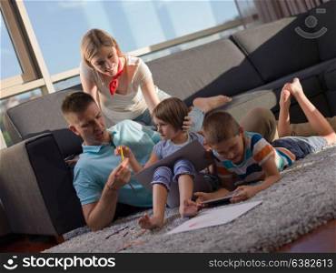 Happy Young Family Playing Together at home using a tablet and a children&rsquo;s drawing set