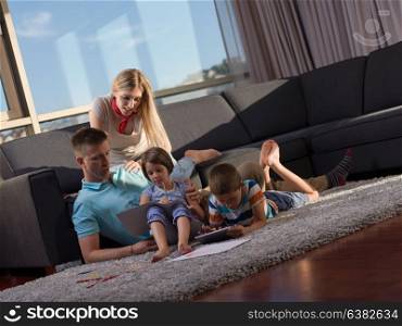 Happy Young Family Playing Together at home using a tablet and a children&rsquo;s drawing set