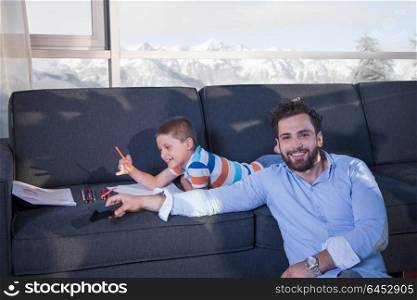 Happy Young Family Playing Together on sofa at home using a tablet and a children&rsquo;s drawing set
