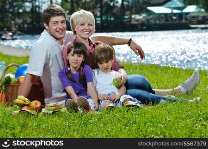 Happy young family playing together with kids and eat healthy food in a picnic outdoors