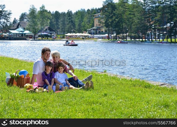 Happy young family playing together with kids and eat healthy food in a picnic outdoors