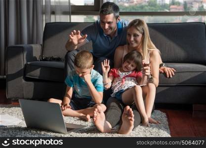 Happy Young Family Playing Together with laptop computer at home sitting on the sofa
