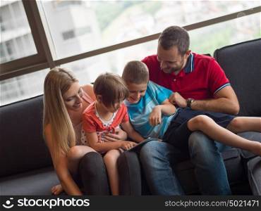 Happy Young Family Playing Together with tablet at home sitting on the sofa