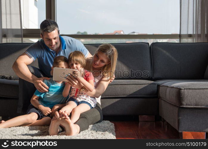 Happy Young Family Playing Together with tablet at home sitting on the sofa