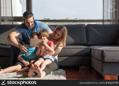 Happy Young Family Playing Together with tablet at home sitting on the sofa