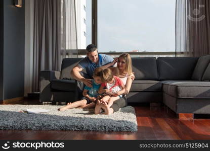 Happy Young Family Playing Together with tablet at home sitting on the sofa