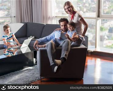 Happy Young Family Playing Together with tablet at home sitting on the sofa