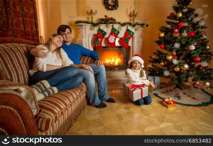 Happy young family relaxing near fireplace on Christmas
