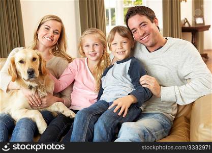 Happy young family sitting on sofa holding a dog