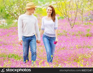Happy young family walking in spring park, holding hands, rural meadow, fruits garden, enjoying vacation