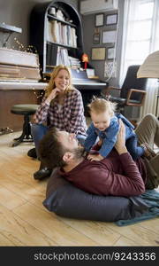 Happy young family with cute girl playing on the floor at rustic room