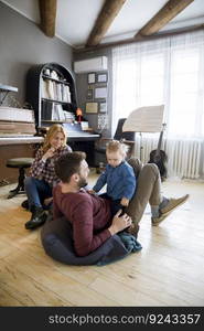 Happy young family with cute girl playing on the floor at rustic room