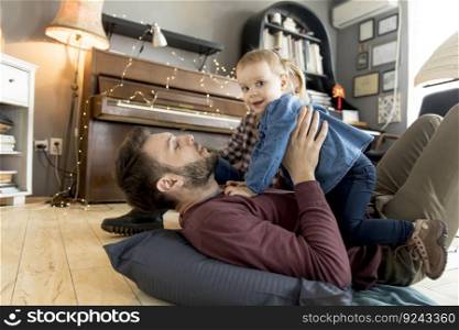 Happy young family with cute girl playing on the floor at rustic room