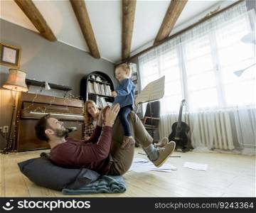 Happy young family with cute girl playing on the floor at rustic room