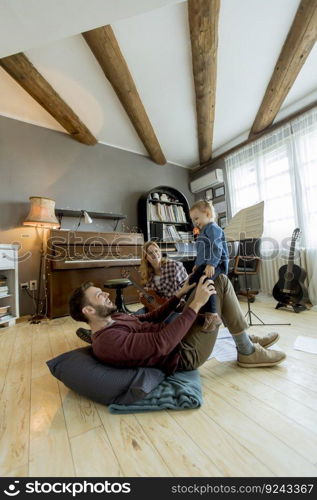 Happy young family with cute girl playing on the floor at rustic room