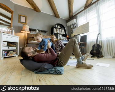 Happy young family with cute girl playing on the floor at rustic room