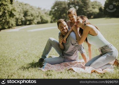 Happy young family with cute little daughter having fun in park on a sunny day