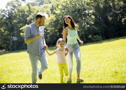 Happy young family with cute little daughter running in park on a sunny day