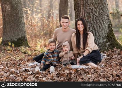 happy young family with two little children relaxing and having fun in autumn park on sunny day. happy young family with two little children relaxing and having fun in autumn park on sunny day.