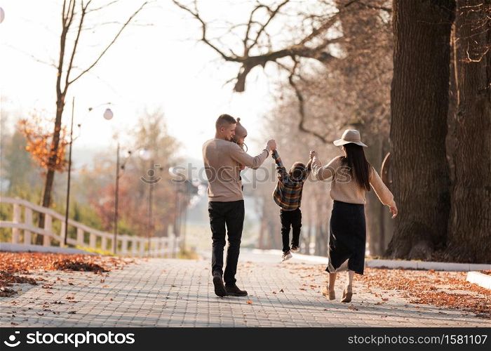 happy young family with two little children walking and having fun in autumn park on sunny day. happy young family with two little children walking and having fun in autumn park on sunny day.