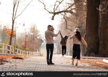 happy young family with two little children walking and having fun in autumn park on sunny day. happy young family with two little children walking and having fun in autumn park on sunny day.