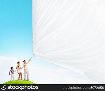 Happy young family. Young family of three pulling blank banner. Place for text