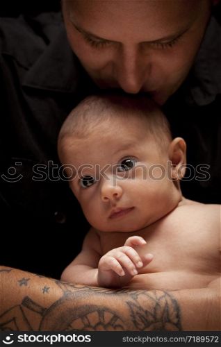 Happy Young Father Holding His Mixed Race Newborn Baby Under Dramatic Lighting.